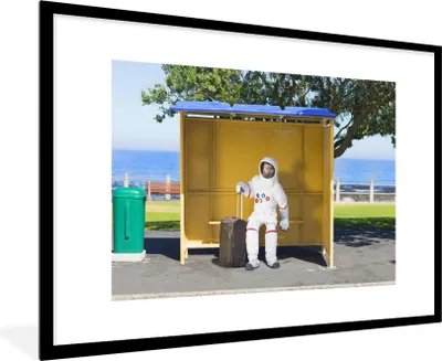 Produktbild von MuchoWow® MuchoWow® Gerahmtes Poster Komischer Astronaut in einem Buswartehäuschen 90x60 cm - Poster mit zchwarzem Bilderrahmen - Wanddekoration - Fotos