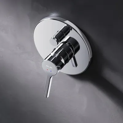 A close-up shot of a chrome shower faucet mounted on a textured gray wall.
