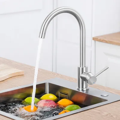 A kitchen sink with a faucet running water over fruit.