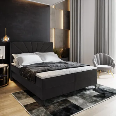 A modern bedroom with a boxspring bed, accent wall, and chair.