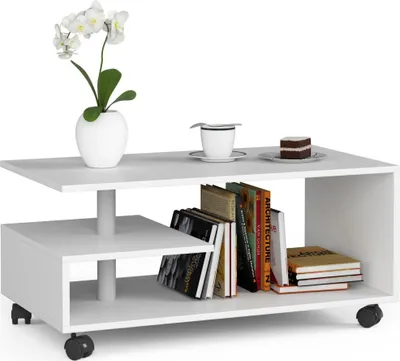 A white, modern coffee table with tiered shelving, decorated with a potted orchid, a cup and saucer, a slice of cake, and several books.