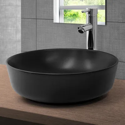 A black ceramic sink on a wooden countertop with a modern faucet and tiled wall in the background.