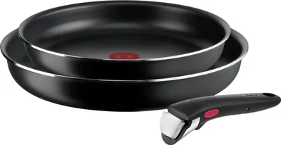 Two black frying pans stacked on top of each other, with a detachable black handle in the foreground.