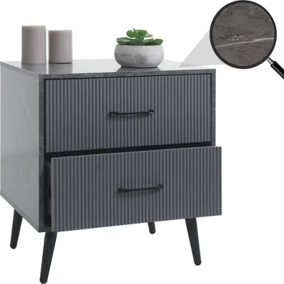 A modern gray nightstand with two drawers and a marble-like finish, decorated with two candles and a small potted plant. A magnifying glass highlights a detail on the surface.