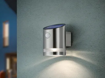 A silver solar-powered wall light is mounted on a textured gray wall.