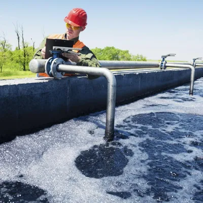 A worker in safety gear inspects equipment at a water treatment facility.