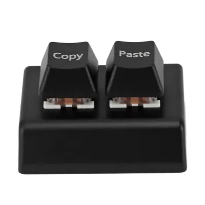 A close-up studio shot of a black programmable keyboard with two keys labeled 'Copy' and 'Paste'.