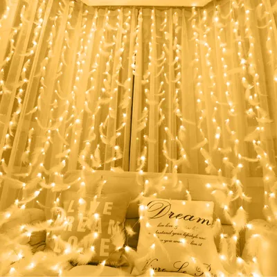 A bed decorated with feather string lights and pillows.