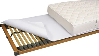 A mattress protector is shown being placed on a slatted bed base, with a mattress partially covering it.