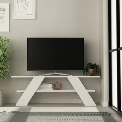 A modern white TV stand with shelves, holding a TV and decorative items, in a well-lit room.