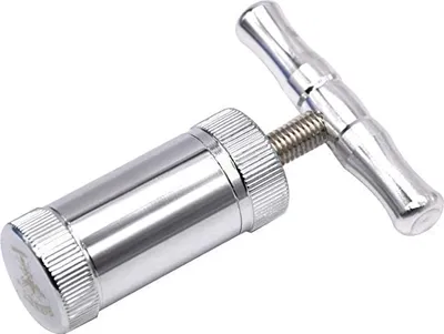 A silver-colored pollen press tool is shown against a white background.