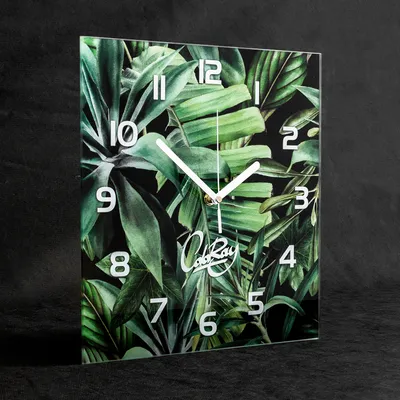 A square wall clock with a tropical leaf pattern and white clock hands and numbers.