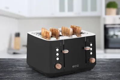 A black four-slice toaster with toast in it, placed on a dark wooden table in a kitchen setting.