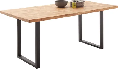 A wooden dining table with black metal legs, shown from a diagonal angle.
