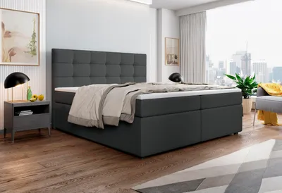 A bedroom scene with a bed, nightstand, and a window overlooking a city.