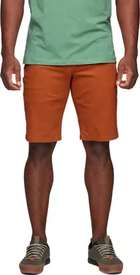 Mann trägt orangefarbene Stretch Font Shorts von Black Diamond; kombiniert mit einem grünen T-Shirt und grauen Sneakers.