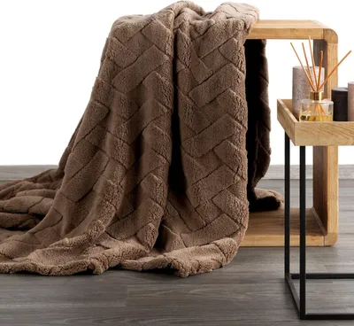 A brown blanket is draped over a wooden cube next to a small wooden tray with decorative items.