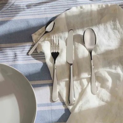 A set of cutlery laid out on a striped tablecloth and a white cloth.