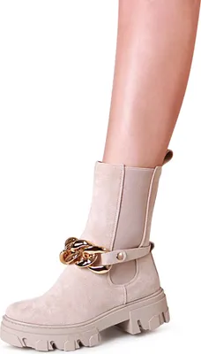 A close-up shot of a woman's leg wearing a beige boot with a gold chain detail.