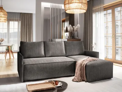 A modern living room with a gray sectional sofa, ottoman, and a throw blanket.