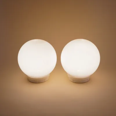 Two white spherical solar lights are shown on a light brown background.