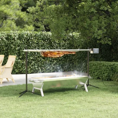 A rotisserie grill with meat cooking on it, set up in a backyard with lush green hedges and trees.