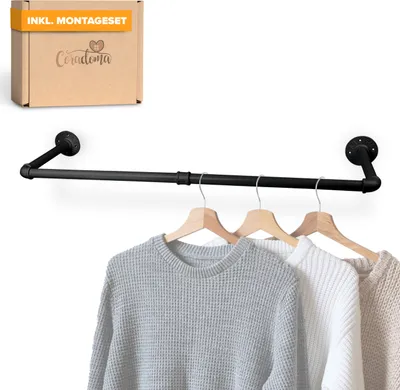 A black metal pipe clothing rack mounted on a white wall, with three sweaters hanging on it.