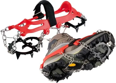 A pair of ice cleats attached to hiking boots, shown against a white background.