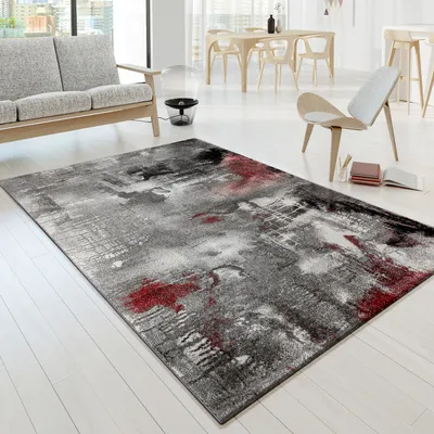 A modern living room with a sofa, dining table, chairs, and a rug.