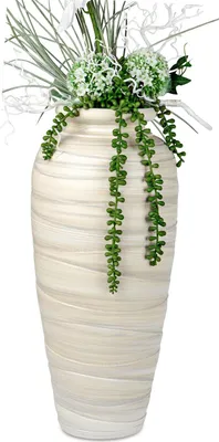 A tall, cream-colored ceramic vase with a textured, wavy pattern, filled with artificial greenery and white decorative elements.