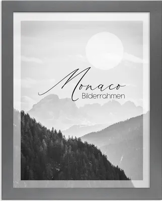 A framed black and white landscape photograph of mountains and trees, with a circular sun or moon in the sky.