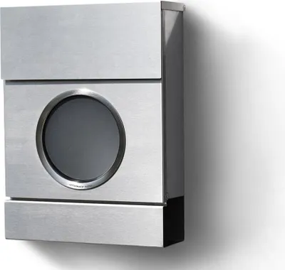 A modern, brushed metal mailbox mounted on a white wall, casting a shadow.