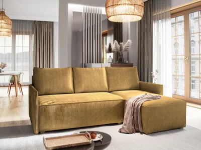 A modern living room with a yellow sectional sofa and ottoman, decorated with dried flowers and a woven pendant light.