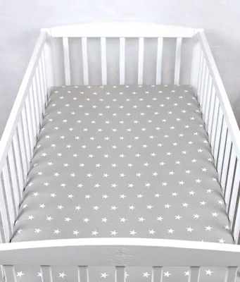 A close-up view of a white crib with a gray fitted sheet featuring a white star pattern.