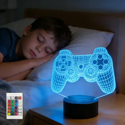 A young boy sleeping in bed next to a glowing blue 3D game controller lamp.