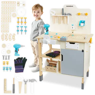 A young boy stands next to a wooden toy workbench with various tools and accessories.
