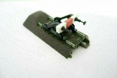 A close-up, slightly angled view of a model train track end piece with a buffer stop attached, set against a plain white background.