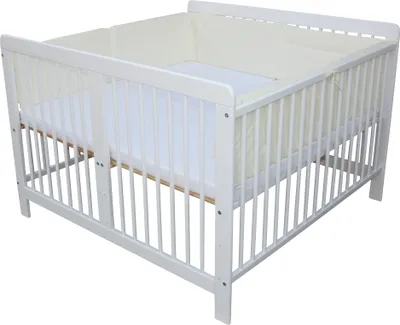 A white wooden crib with beige bedding and a white mattress, shown from a slightly elevated side angle against a white background.