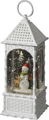 A white decorative lantern with a Christmas scene inside, featuring a snowman, reindeer, and trees, with glitter and lights.