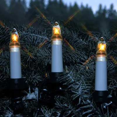 Three candle-shaped lights are attached to a dark green, possibly frosted, evergreen branch.