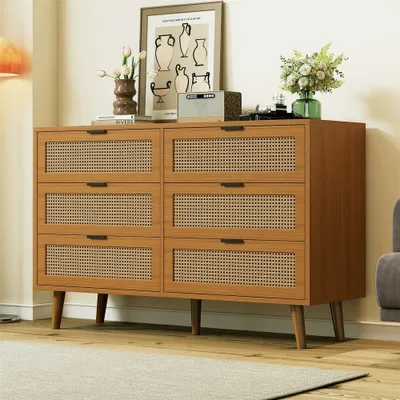 A wooden dresser with cane-front drawers is shown in a room with a rug and a framed picture on top.
