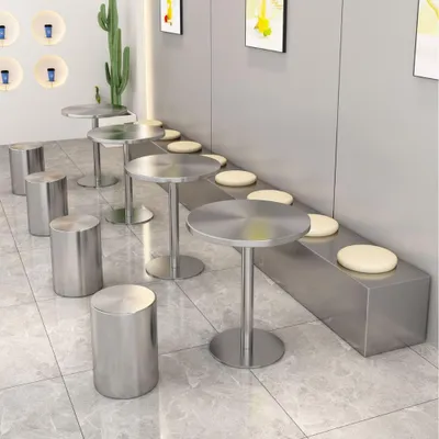 A cafe or restaurant seating area with small round tables and stools, and a long bench with cushions.