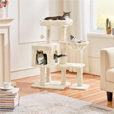 Three cats are playing on a beige cat tree in a living room.