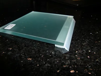 A close-up shot of a glass plate with a protective silicone seal on a dark, speckled countertop.