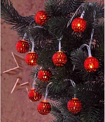 A string of red, oriental-style Christmas lights on a dark green Christmas tree.