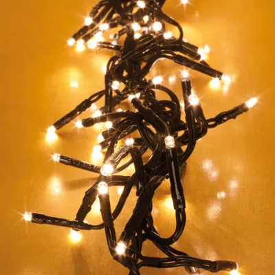 A close-up view of a string of warm white LED cluster lights on a textured orange background.