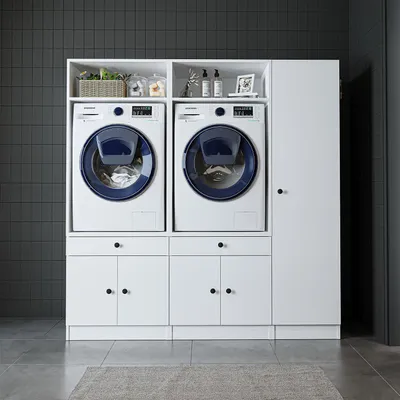 A laundry room setup with two washing machines and storage cabinets.