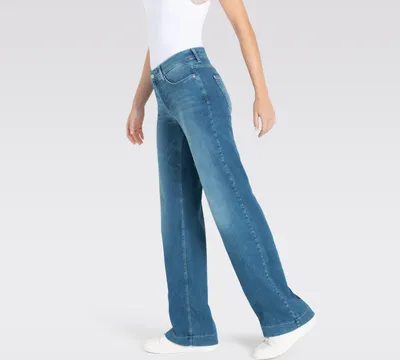 A person wearing blue jeans and a white top, shown from the side against a white background.