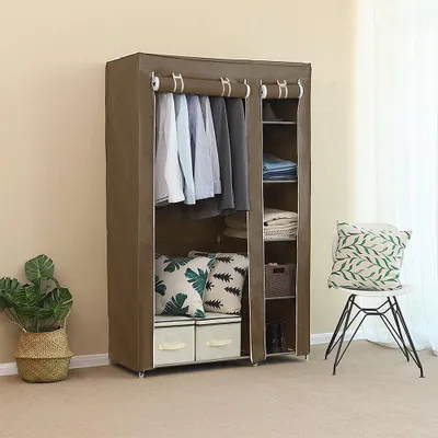 A portable fabric wardrobe is shown, filled with clothes and accessories, placed on a carpeted floor.