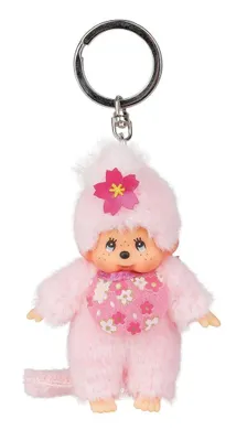 A pink Monchhichi keychain with a flower bib and flower on its head, against a white background.